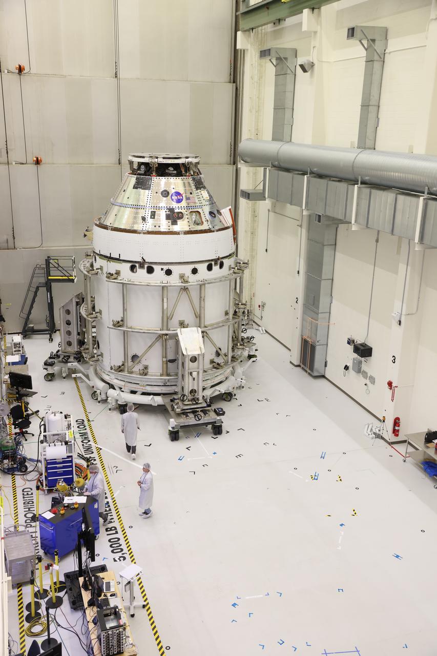 The Artemis II Orion spacecraft sits in the transfer aisle in the Neil A. Armstrong Operations and Checkout Building at NASA’s Kennedy Space Center in Florida following successful installation of three spacecraft adapter jettison fairings on Wednesday, March 19, 2025. The fairings encapsulate the service module and protect the solar array wings, shielding them from the heat, wind, and acoustics of launch and ascent, as well as help redistribute the load between Orion and the massive thrust of the SLS (Space Launch System) rocket during liftoff and ascent. Once the spacecraft is above the atmosphere, the three fairing panels will separate from the service module reducing the mass of the spacecraft.